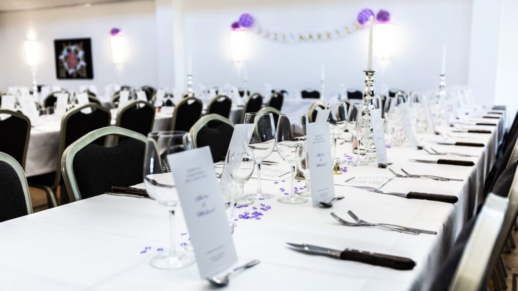 En elegant festdukning med vita dukar, glas och menyer – redo för firande på Hotel Skansen.