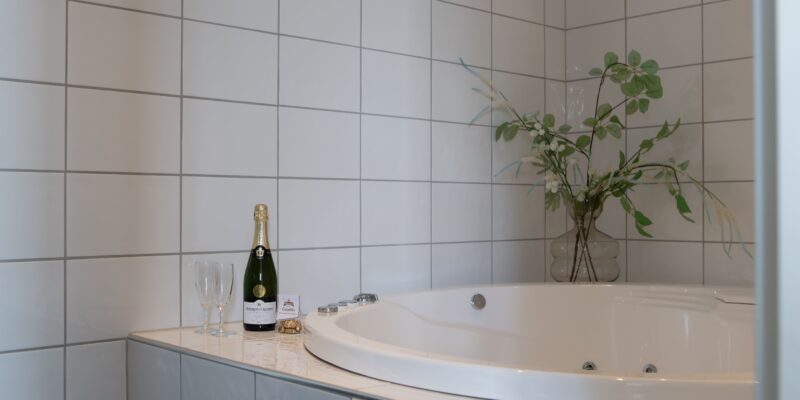 På bildens syns badrummet i en minisvit hos Hotel Skansen på Öland. I badrummet finns jacuzzi, dusch, toalett, handfat och spegel.