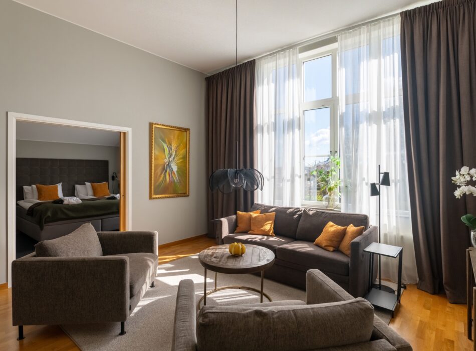 På bildens syns sviten hos Hotel Skansen på Öland. Rummet består av två rum, ett vardagsrum med soffgrupp och matplats samt en sovrum med dubbelsäng och skrivbord.