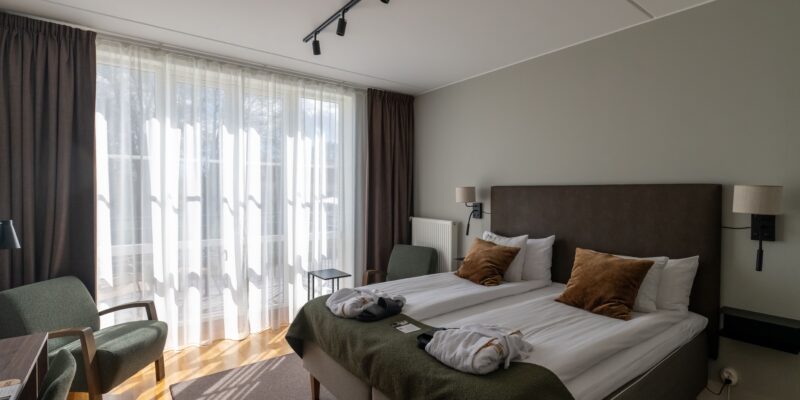 På bildens syns ett standardrum i Tingshuset hos Hotel Skansen på Öland. Rummet har en dubbelsäng, en fotölj och ett skrivbord