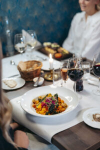 En färgstark vegetarisk rätt serverad med vin och levande ljus, en del av den kulinariska upplevelsen på Hotel Skansen.