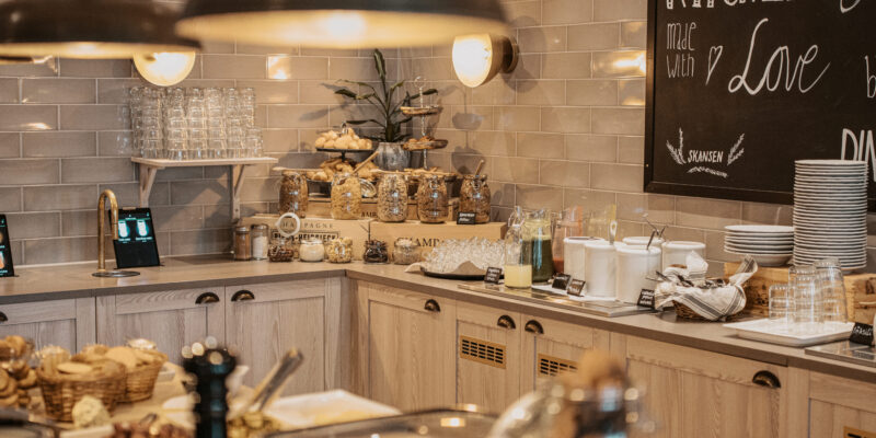 En välfylld frukostbuffé med juicer, flingor och nybakat bröd, presenterad med omsorg på Hotel Skansen.