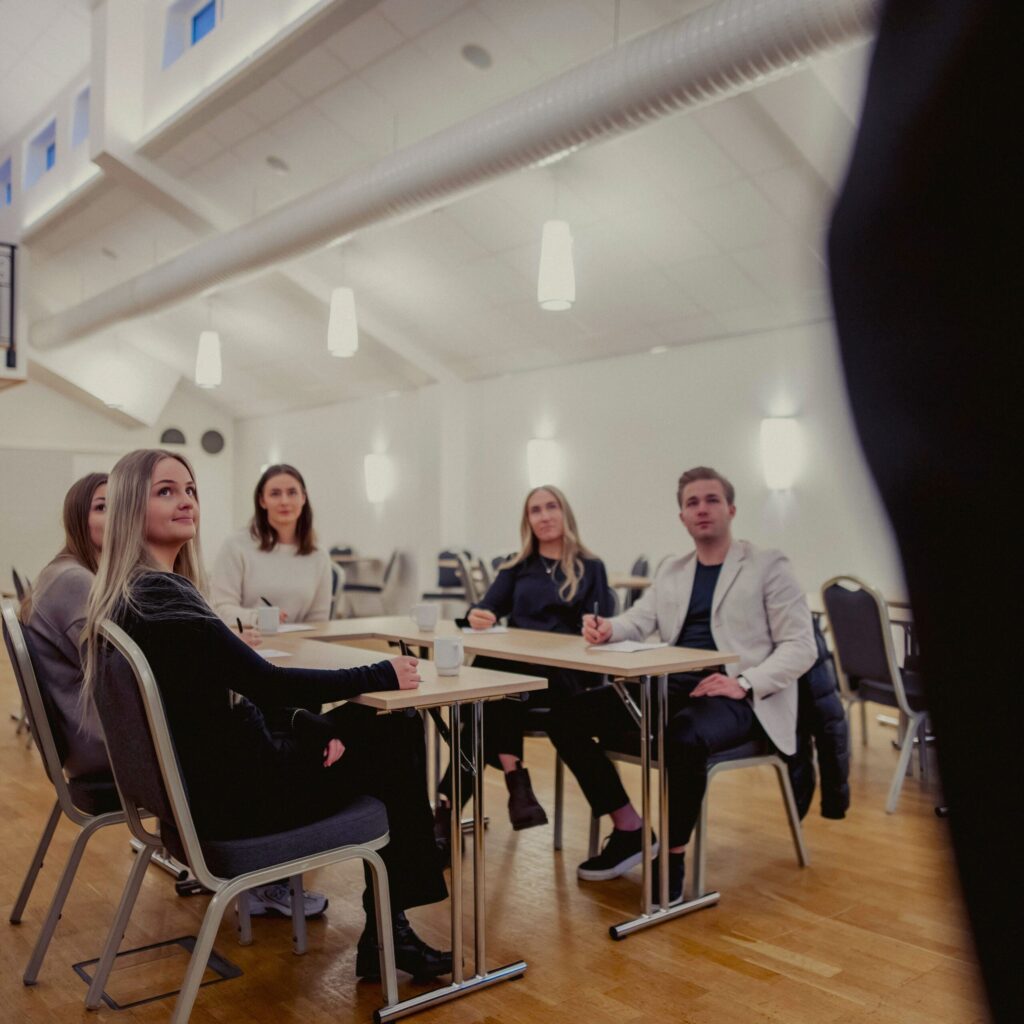 En grupp konferensdeltagare lyssnar fokuserat i en ljus och modern möteslokal på Hotel Skansen.