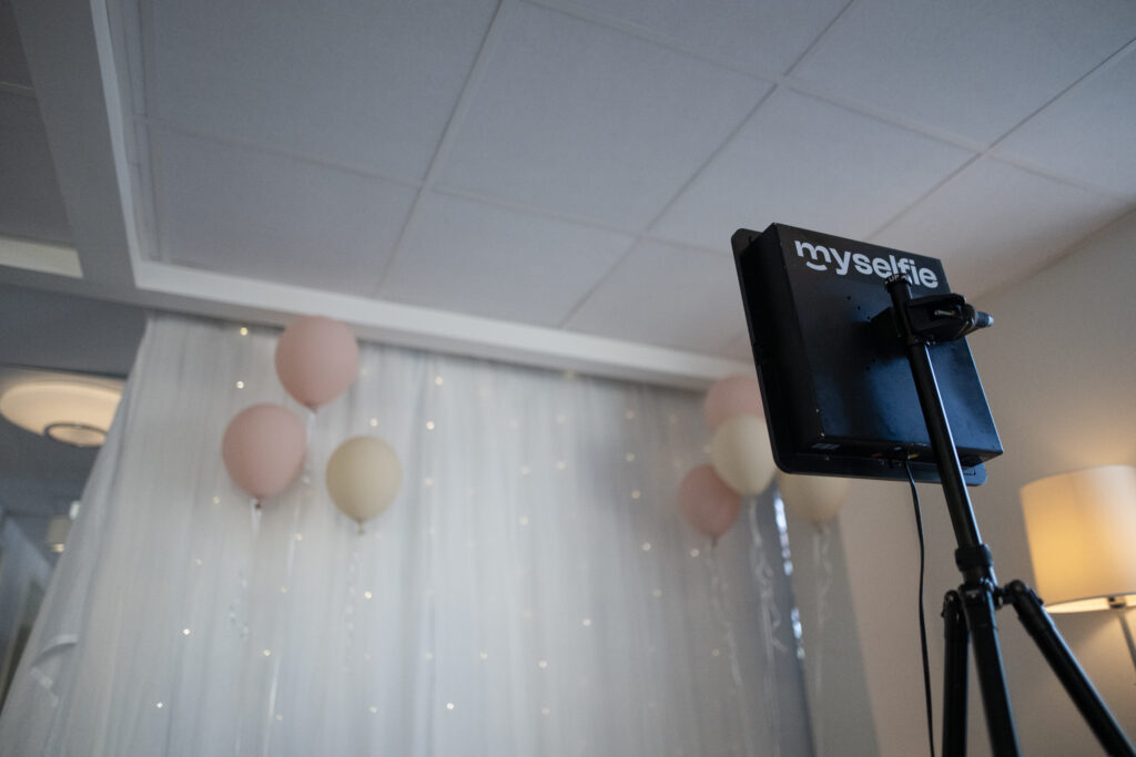Bilden föreställer en selficam som står riktad mot en vit fotovägg med ljusslingor och ballonger hos Hotel Skansen Öland